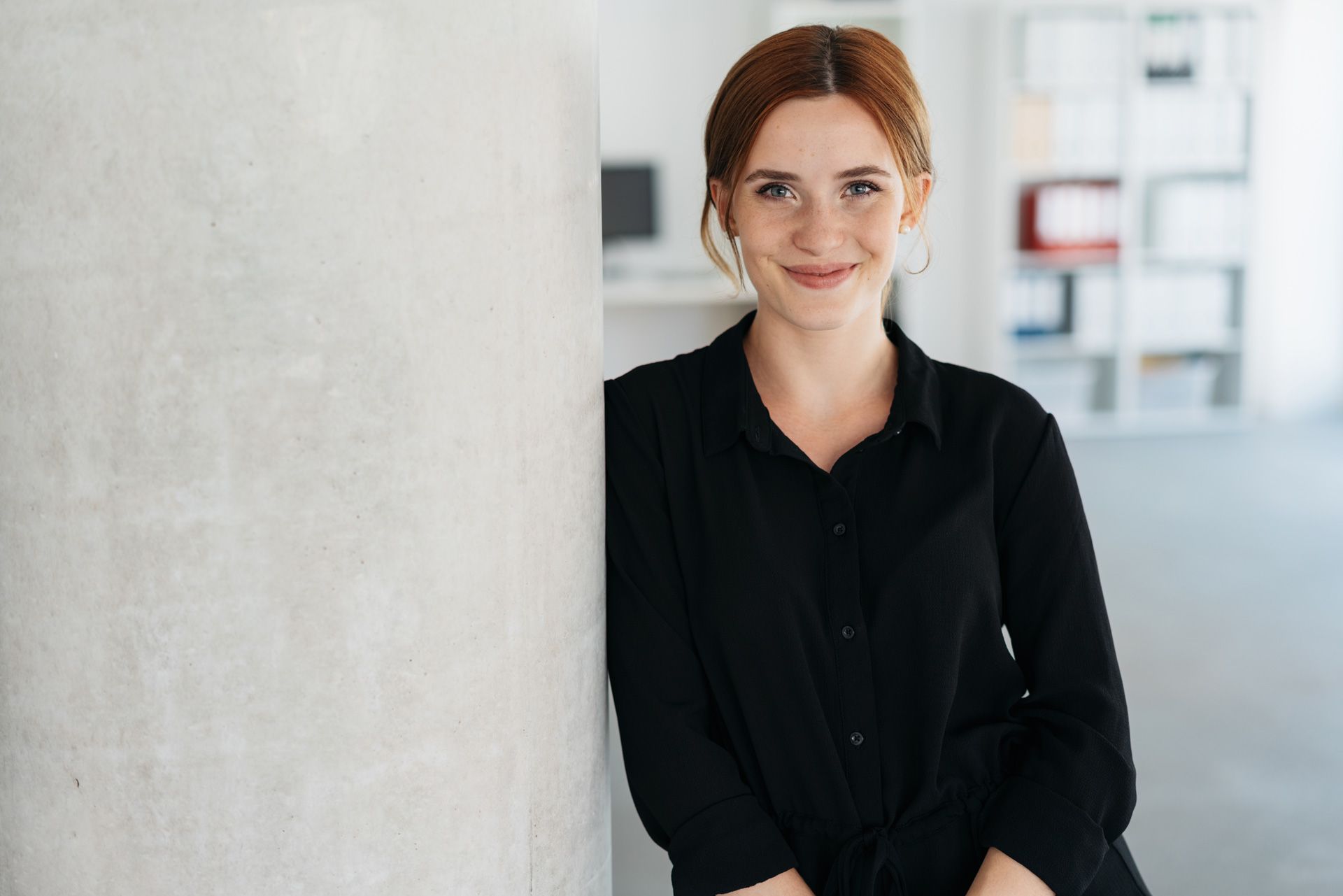 Junge Frau in den Räumlichkeiten ihres Arbeitsplatzes. 